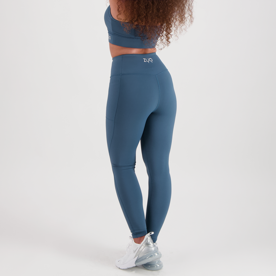 View from back. Model legs in full-length leggings in deep, dusty teal colour