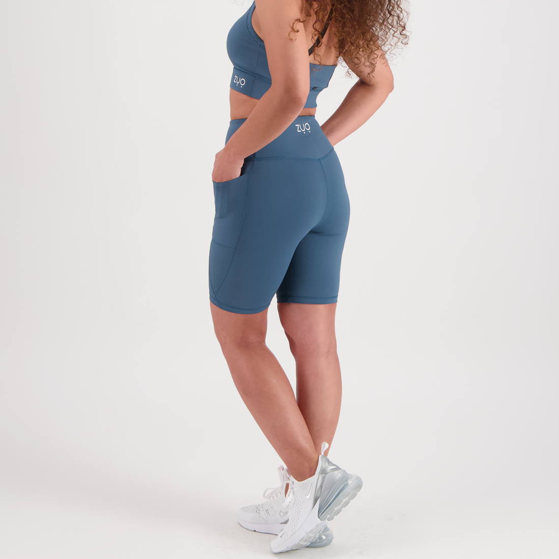 Side view, model in mid-length shorts in Arctic Teal, a dusty blue-green colour