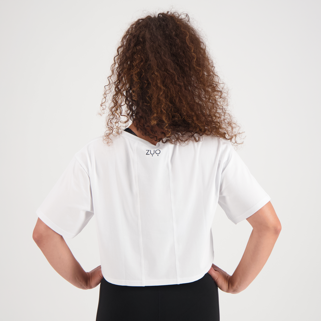 View from back of model with curly hair in Keep Up, high waisted black leggings and ZUO Apparel Branded Box Tee. White background.