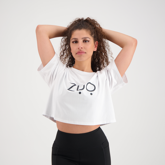 View from front of model with curly hair, arms up in Keep Up, high waisted black leggings and ZUO Apparel Branded Box Tee. White background.